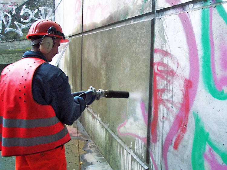 Нанесение очистителя на стену с граффити